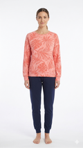 Woman wearing a pink floral long-sleeve top and navy pants on a white background