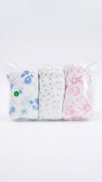 A three-pack of folded baby tights or socks in a clear plastic bag, featuring a blue floral pattern, a white pattern with small gray stars, and a pink floral pattern.
