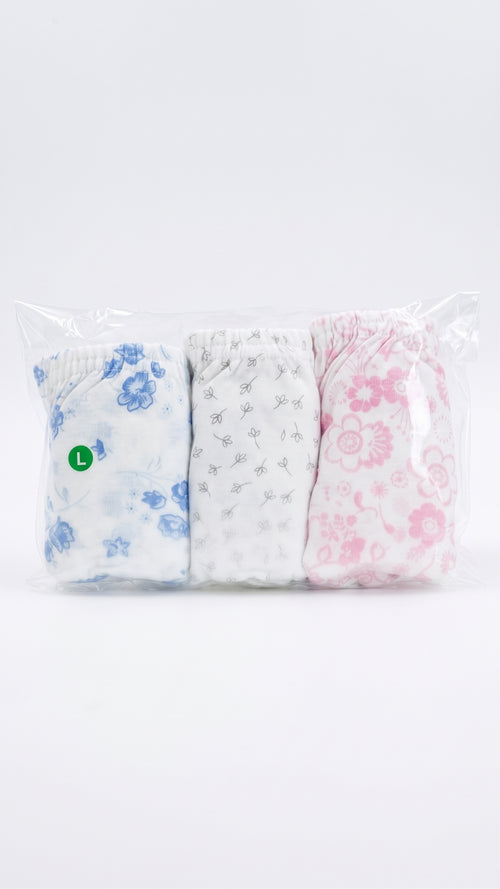 A three-pack of folded baby tights or socks in a clear plastic bag, featuring a blue floral pattern, a white pattern with small gray stars, and a pink floral pattern.