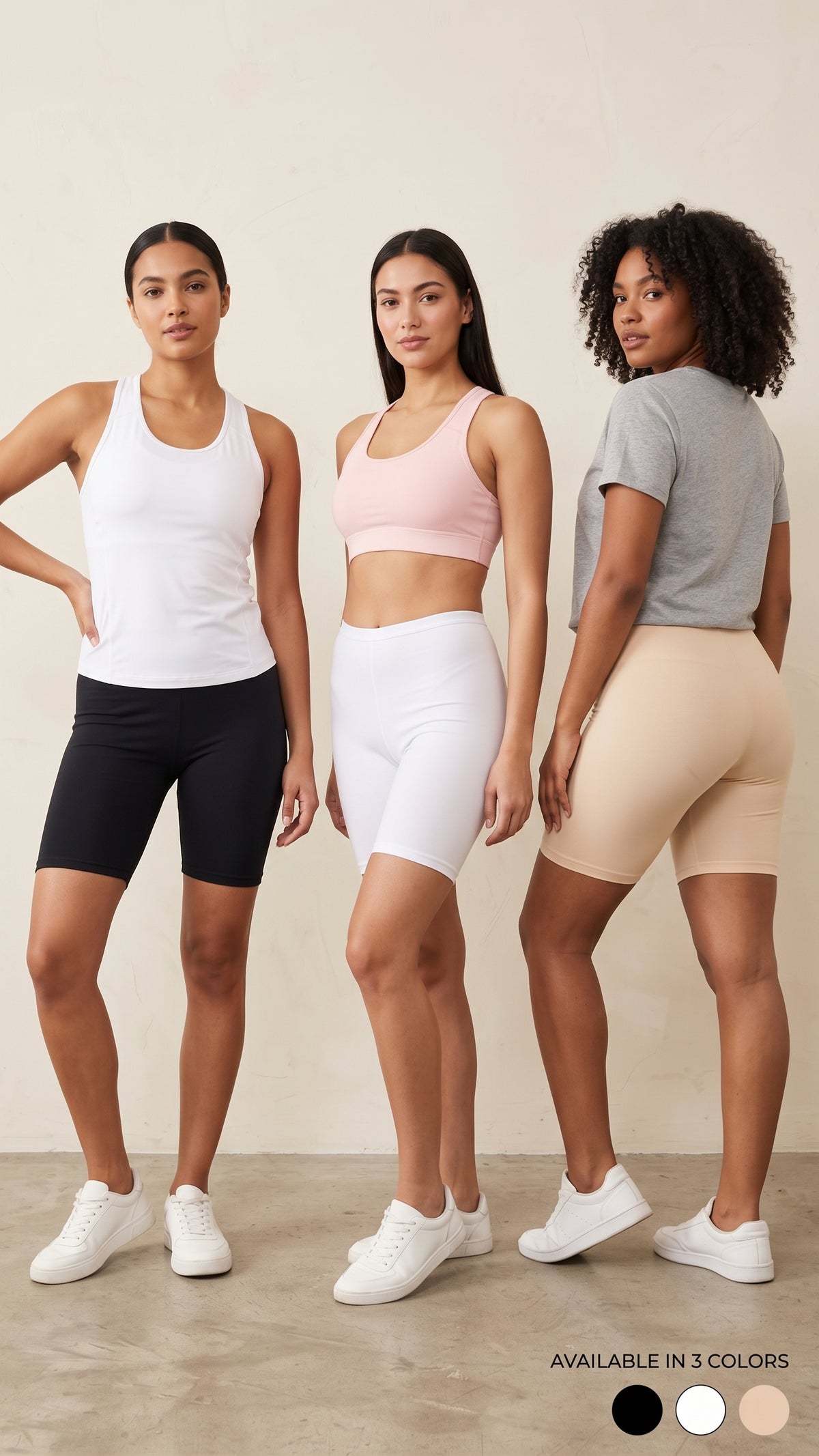 Three women modeling fitted athletic biker shorts in different colors: black, white, and beige. The center model wears a light pink sports bra, and the image includes a small text note at the bottom right reading 'AVAILABLE IN 3 COLORS' above circular color swatches.