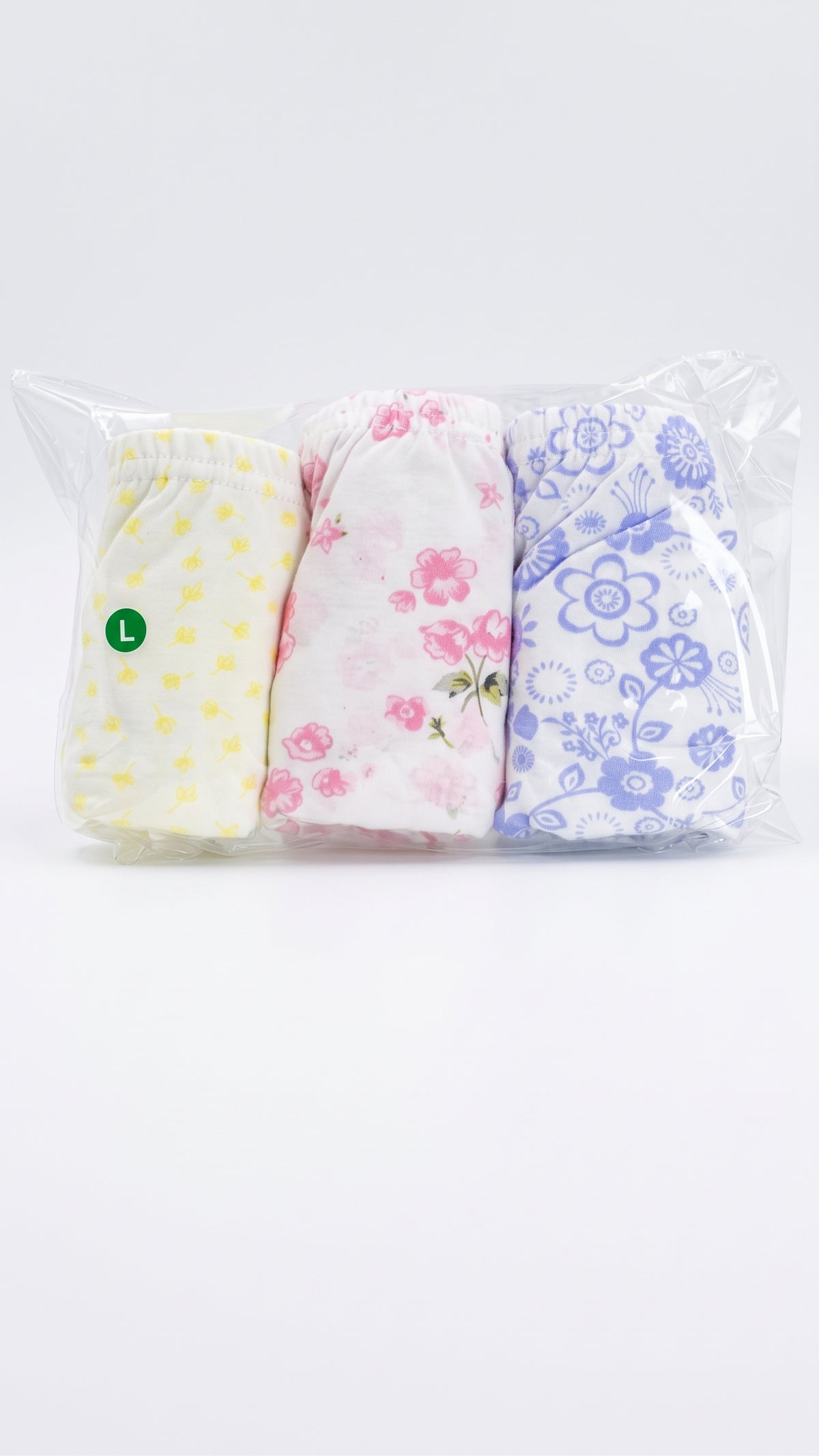 Three pairs of folded baby shorts in a clear plastic bag, featuring yellow polka dots, pink floral print, and blue floral print on white backgrounds.