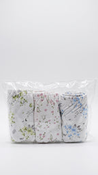 Three pairs of folded baby pants in a clear plastic bag, featuring white backgrounds with green, pink, and blue floral prints.