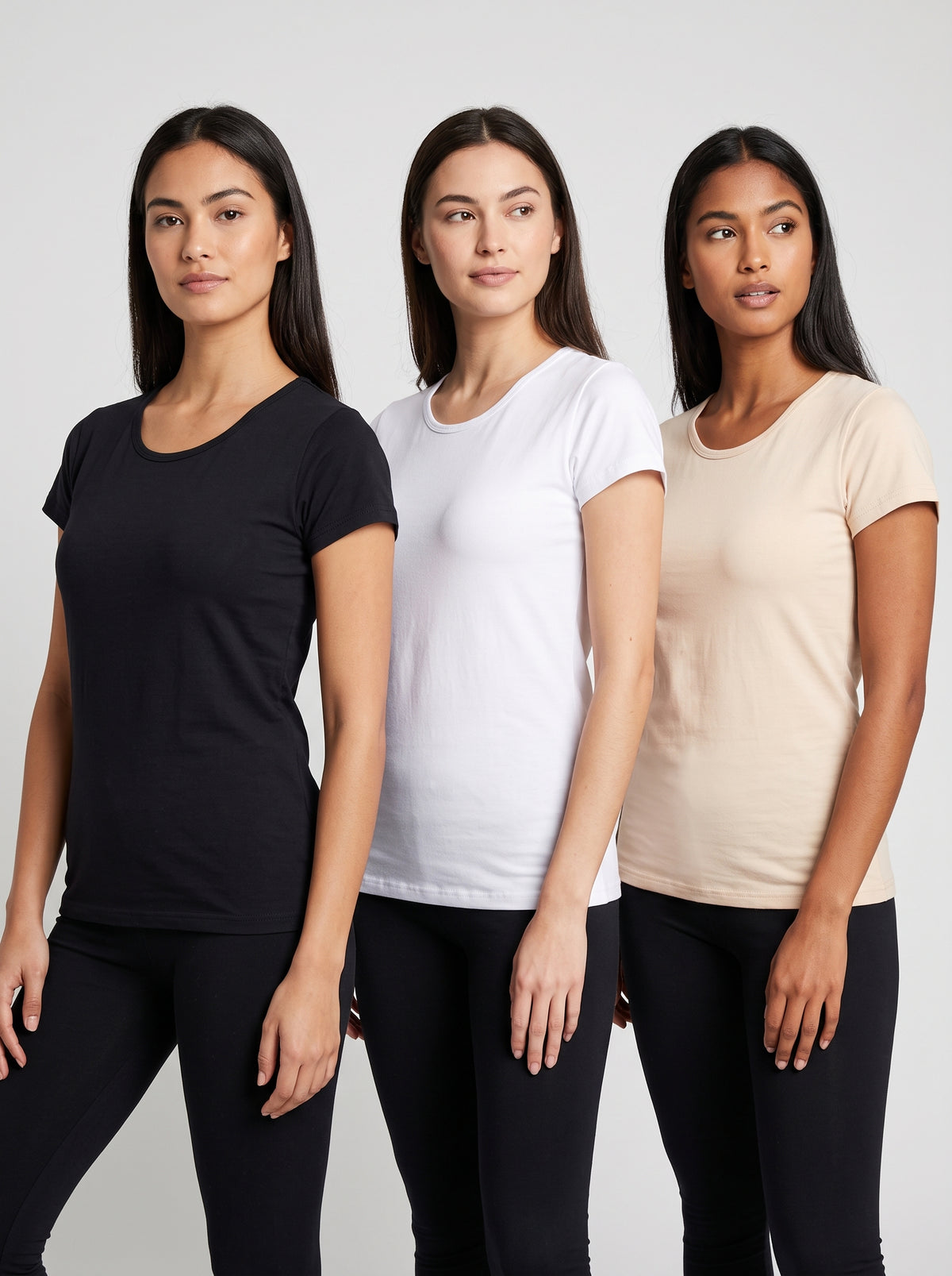 Three women modeling short-sleeve crew-neck t-shirts in black, white, and light beige, paired with black leggings, against a light gray studio background.