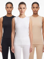 Three models standing side by side wearing sleeveless compression-style tops in black, white, and beige, paired with matching leggings, against a plain light background.