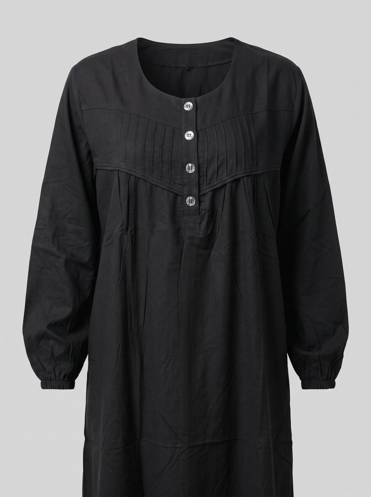 A black long-sleeve dress with a round neckline, three front buttons, and a gathered chest detail, shown against a solid gray background.