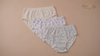 Three pairs of Abdelhady Homewear high-waisted cotton briefs with delicate floral and star patterns, laid flat on a peach background.